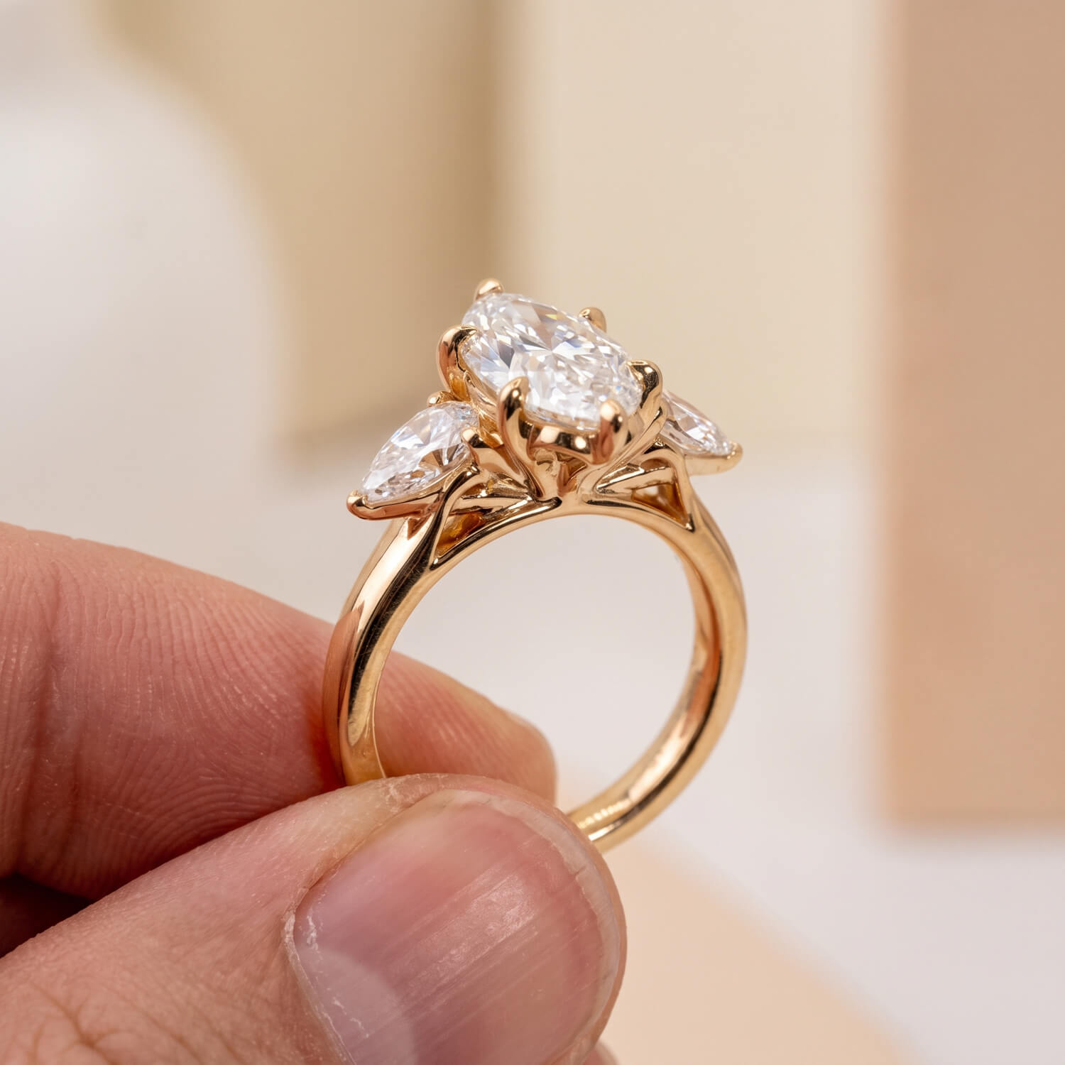 Open floral gallery beneath three-stone diamond engagement ring