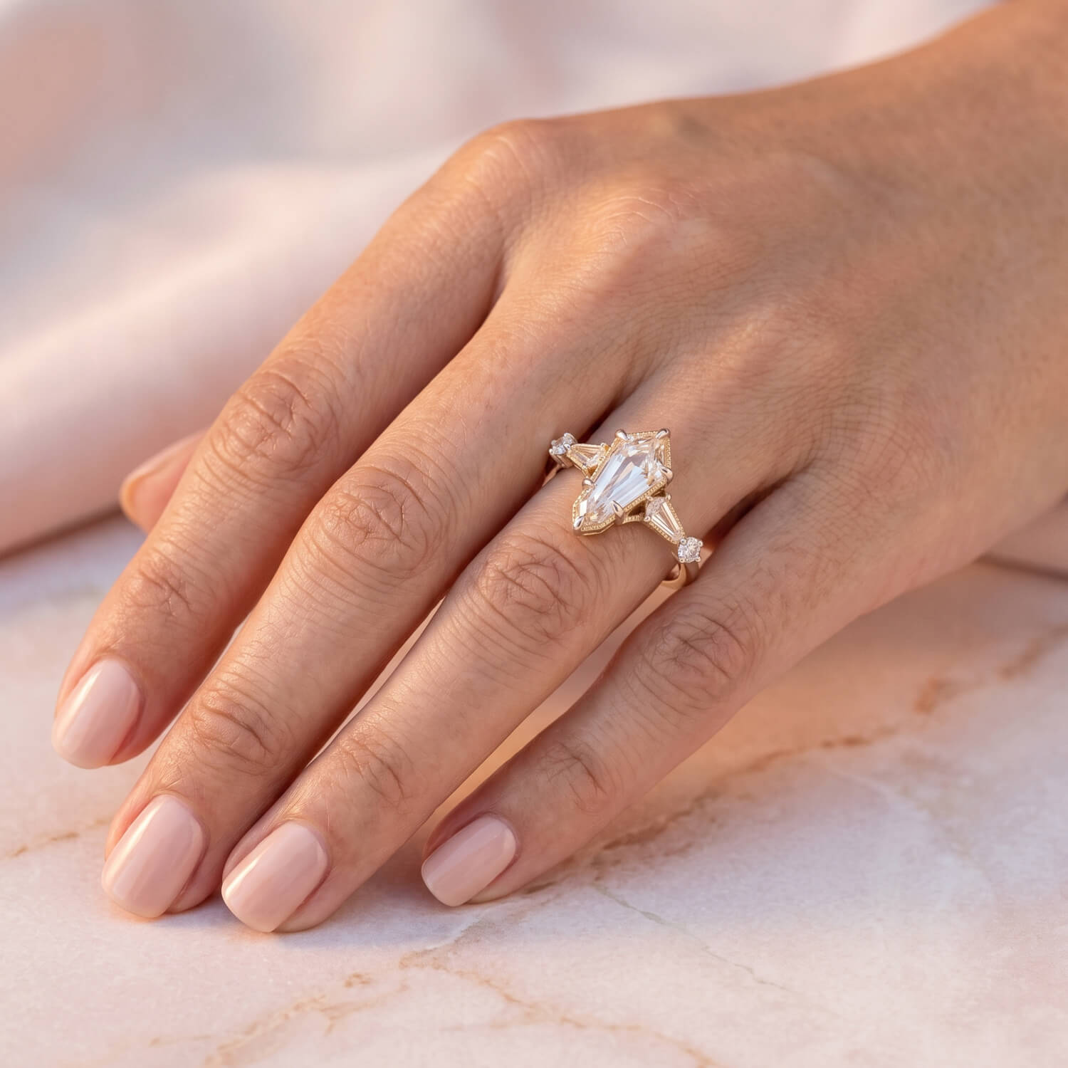 Custom kite-shaped diamond engagement ring shown at wearing scale